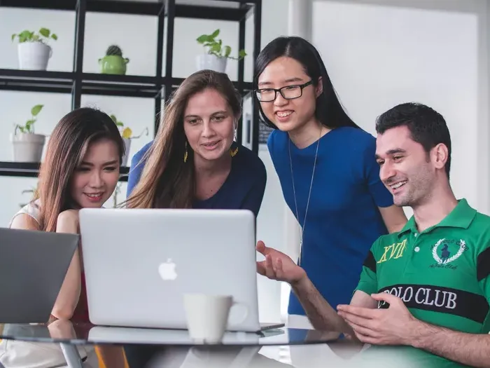 Diverse business team gathered around a laptop during a meeting, representing collaboration on Town Service Connect